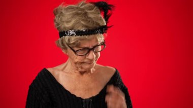 Dişleri olmayan, cildinde kırışıklıklar olan yaşlı ve komik bir kadının portresi kırmızı arka planda izole bir şekilde poz verdirme düşüncesinin patlamasıyla ilgili harika bir fikir veriyor.