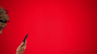 Komik, yaşlı bir kadın çerçevede yürürken akıllı telefonundan biriyle konuşuyor. Duruyor ve kareye doğru devam ediyor. Kırmızı arkaplanda izole