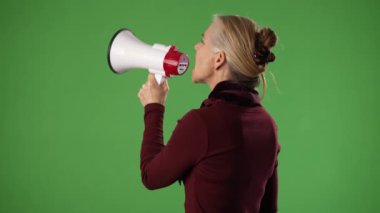 Olgun sarışın kadının megafona bağırışının yan görüntüsü. Yeşil ekran krom anahtarında izole edilmiş.
