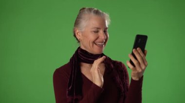 Yeşil Ekran arkaplanı ve portresi ile gülümseyen olgun bir kadın kameralı konuşmaya bak canlı görüntülü konferans görüşmesi yap ve akıllı telefon görüntülü sohbet kavramını kullan.