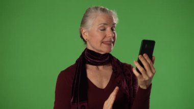 Yeşil Ekran arkaplanı ve portresi ile gülümseyen olgun bir kadın kameralı konuşmaya bak canlı görüntülü konferans görüşmesi yap ve akıllı telefon görüntülü sohbet kavramını kullan.