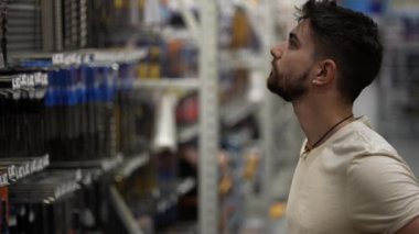 Hırdavatçı dükkanındaki elektrikli aletler için parça arayan bir adam..