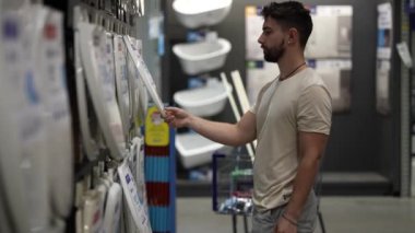 Hırdavatçı dükkanının sıhhi tesisat bölümünde klozet kapağı almak ve karşılaştırmak için yakın çekim.