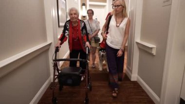 Aile, yaşlılar yurdunda ya da koridorun aşağısındaki huzurevinde yaşlı bir kadınla köpek gezintisi yapıyor..