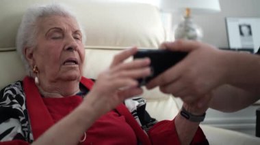 Torunu telefonunda fotoğraflarını gösterirken yaşlı büyükannesinin aşırı derecede gülümsemesi anılarını paylaşıyor..