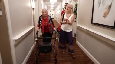 Aile, yaşlılar yurdunda ya da koridorun aşağısındaki huzurevinde yaşlı bir kadınla köpek gezintisi yapıyor..