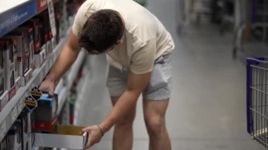 Charlottesville, VA, ABD - 07 23 2024: Hırdavatçı deposundaki alışveriş arabasına ev yenileme projesi için kapı tokmakları koyan adama yakın çekim.