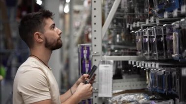 Hırdavatçı deposundan çıkan ve telefon kullanarak eşya arayan adama yakın çekim..