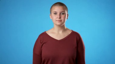 Gülümseyen kafa sallayarak etrafınıza bakın. Çift cinsiyetli olmayan, 30 'lu yaşlarda genç bir kadın. Mavi arka plan stüdyosunda yalnız poz veriyor. Portre samimi duygular yaşam tarzı konsepti.