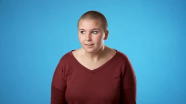 Çift cinsiyetli olmayan beyaz kadın portresi. 20 'li yaşlarda. Mavi arka plan stüdyosunda izole edilmiş bir sırrı anlatmak için el ele dolaşır.