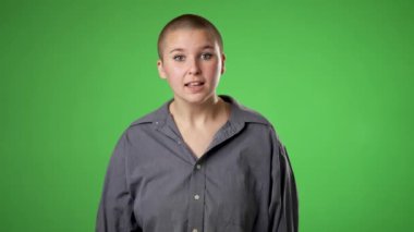Gülümseyen mutlu cinsiyet akışının portresi. Çift cinsiyetli olmayan, 20 'li yaşlarda, gülümseyen ve elleri yeşil ekranda izole bir şekilde bana işaret eden genç bir kadın..