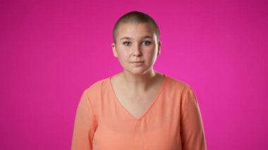 Gülümseyen genç kadın pembe arka plan stüdyosunda yirmili yaşlarda poz veriyor. İnsanlar samimi duygular, yaşam tarzı konsepti. Çekici bir gülümsemeyle kameraya bakıyorum.