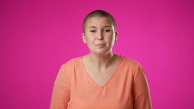 Cinsiyet sıvısı, çift taraflı olmayan, yalvaran 20 'li yaşlarda, dua ederken el ele tutuşan, pembe arka plan stüdyosunda parmaklarını çapraz tutarak dua eden bir kadın. Halk yaşam tarzı konsepti