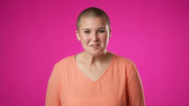 İkili cinsiyet değişmeyen 20 'li yaşlardaki genç bir kadının portresi mutlu bir gülümseme sergiliyor pembe arka plan stüdyo resmine izole edilmiş.