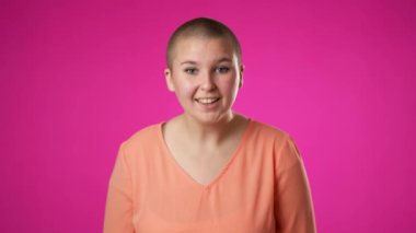 İkili cinsiyet değişmeyen 20 'li yaşlardaki genç bir kadının portresi mutlu bir gülümseme sergiliyor pembe arka plan stüdyo resmine izole edilmiş.
