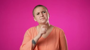Çift cinsiyetli olmayan, değişken, 20 'li yaşlarda genç bir kadın pembe arka planda poz veren fikirlerin patlamasını gösteren akıllara durgunluk veren bir jest yapıyor..
