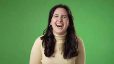 Heyecanlı mutlu 20 'li yaşlarda bir kadın. Gülümse, gülümse, komedi filmi izle, işaret parmağını yeşil ekran arka plan stüdyo resmine iliştir..