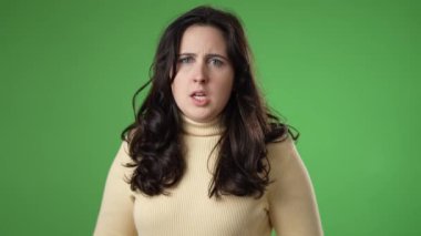 Kızgın ümitsizliğin portresi, yeşil ekranda izole edilmiş 20 'li yaşlarda genç bir kadının yumruklarına sinirlendi..