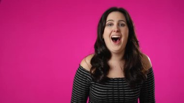 Gülümseyen güzel esmer kadın portresi. 20 'li yaşlarda, pembe arka plan stüdyosunda yalnız poz vermiş. İnsanlar samimi duygular yaşam tarzı konsepti.