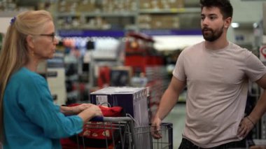 Olgun kadın ve inşaatçı, kereste bölümündeki hırdavatçıda inşaat projesini tartışıyor..