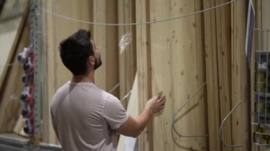 Ahşap kereste üretim ürünlerine bakan ve onları kontrol eden bir adam var. Hırdavatçıdaki kereste bölümünün eğri mi yoksa düz mü olduğunu görmek için..