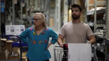 Erkek ve olgun kadın, inşaat projesini tartışmak için alışveriş arabasını hırdavatçıya götürüyor..