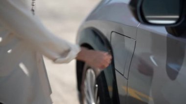 İş kadını el fişini şarj istasyonundan çekmek şehir merkezinde dolaşmadan önce elektrikli arabaya takılır. Çevre dostu şarj edilebilir araba, sürdürülebilir ve temiz enerjiyle çalışıyor.
