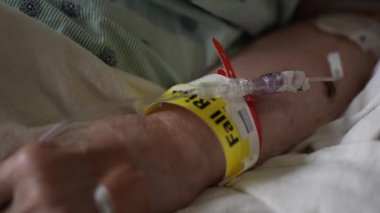 Düşme riski bilekliğinin hastane yatağında yatarken yaşlı kadınların eline takılması.. 