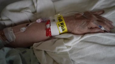 Düşme riski bilekliğinin hastane yatağında yatarken yaşlı kadınların eline takılması.. 
