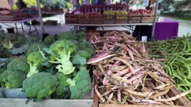Taze yeşil fasulye ve brokoli dolu iki tahta kasanın yakın plan çekimi. Yeşil fasulyeler odaklanırken, brokoli biraz bulanık.. 