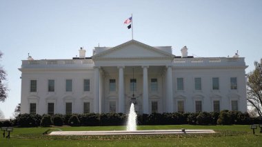 Açık bir bahar günü, Washington, DC 'deki Beyaz Saray' ın, verimli yeşillik ve demokrasiyi sembolize eden zarif mimarisi ve sakin çeşmesini gözler önüne seriyor..