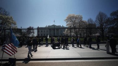 Ziyaretçiler Beyaz Saray 'ın dışında toplanarak bahar manzarasının tadını çıkarırken, federal hükümet parlak bir günde arka planda faaliyet gösteriyor..