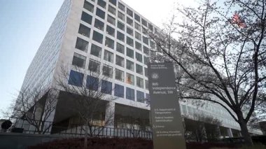 Washington DC, ABD - 03 21 2025: ABD Ulaştırma Bakanlığı Washington DC 'de ayakta duruyor, ilkbaharda filizlenen ağaçların arka planına karşı modern mimari sergileniyor.