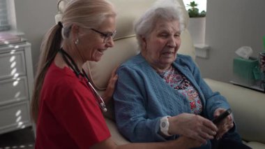 Bakıcı, yaşlı bir kadına sağlık merkezinde yardım eder, hafıza ve duygusal refahı geliştirmek için bağlanma ve etkileşimi teşvik eder..