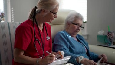 Bir sağlık uzmanı, rahat bir hafıza merkezinde yaşlı bir kadına ilaçlarıyla yardım ediyor. Bakıcı şefkat ve ilgi gösterir..