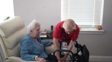 Şefkatli bir bakıcı, sağlık merkezindeki yaşlı bir kadına destek olup, evdeki ilişkileri ve konforlarını güvence altına alır..
