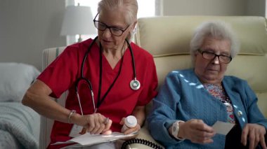 Bakıcı yaşlı bir kadınla iletişim kurar, iyi aydınlatılmış bir sağlık merkezinde bakım ve destek sağlar, bağlanma ve bağlanmayı teşvik eder.