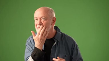 Kıdemli adamın aynada kendine baktığı pov kel kafasındaki saçlarını düzeltiyor. Katı yeşil arka plan, onun ifadesel yüzüne ve hareketlerine odaklanmasını sağlar..