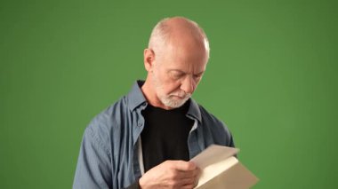 Mutlu, olumlu, düşünceli bir ifadeye sahip olgun bir adam, bu portrede çeşitli duygular sergilerken, katı yeşil bir ekranın önünde bir mektup okuyor..