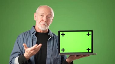 Olgun bir adam, teknolojiyi ve yeniliği sembolize eden yeşil ekranlı bir dizüstü bilgisayar sunar. Bir stüdyoda, kendine güvenen bir girişimci ruhu sergiliyor..