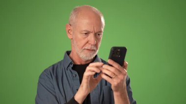Olgun bir adam akıllı bir telefonu tutarken gülümser, yeşil arka plana karşı olumlu bir hareket ile olumlu ifade eder. Ürün duyuruları için mükemmel.
