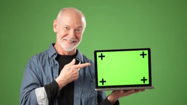 Son sınıf öğrencisi parlak bir stüdyoda oturuyor, güvenle gülümsüyor ve elinde yeşil ekranlı bir dizüstü bilgisayarla başparmak kaldırıyor, sunumlar ve projeler için mükemmel..