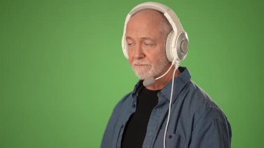 Müşteri hizmetleri kulaklığı takan olgun bir adam katı yeşil ekrana karşı izole edilmiş, müşteriyle konuşurken duygularını ifade ediyor..