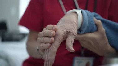 Bir bakıcı, hareket ve konfor aralığını geliştirmek için hastanın parmaklarına ve bileğine nazikçe masaj yapar. Bu kişisel bakım bir sağlık kliniğinde yapılır..