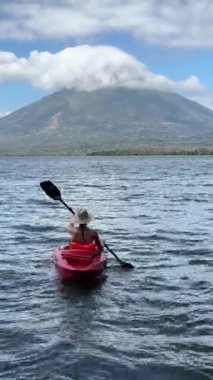 Olgun bir kadının Ometepe Gölü 'nde kayak yaparken çekilmiş dikey videosu arka planda muhteşem Concepcion volkanı Nikaragua' nın güzelliğini gözler önüne seriyor..