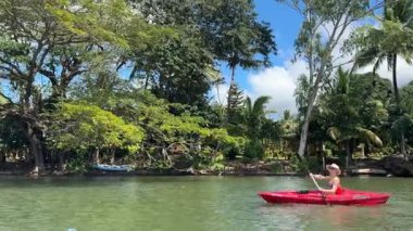 Olgun bir kadın, yemyeşil ve mavi gökyüzü ile çevriliyken Ometepe adasının ve pitoresk volkanın doğal güzelliğinin tadını çıkararak sakin bir gölde kayak yapar..