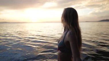 Gülümseyen orta yaşlı kadının yakın plan portresi gün batımında Orta Amerika gölünün sakin sularında duruyor. Tatilinin güzelliğini kucaklayarak neşe saçıyor..