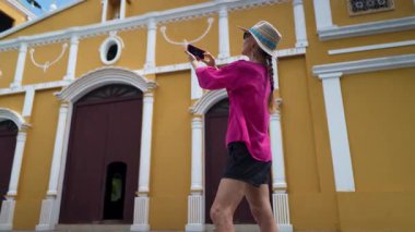 Olgun bir kadın Ometepe Adası 'nda Moyogalpa' nın canlı mimarisini çekerken gülümser. Renkli kilise onun macerası için çarpıcı bir zemin hazırlıyor..