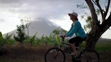 Mutlu bir son sınıf öğrencisi, arka planda muhteşem Concepcion volkanı olan ve Orta Amerika 'nın güzelliğini gösteren Ometepe Adası' nda bisiklet sürüyor..