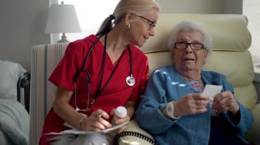 Önlüklü bir hemşire, gün boyunca rahat bir odada notları incelerken, yaşlı bir asistanla sıcak etkileşime girer..
